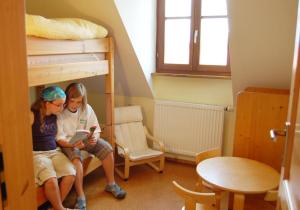 two girls sitting on a bunk bed reading a book at BiolandHof Röttenbacher in Gunzenhausen