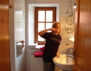 a woman standing in a bathroom brushing her teeth at BiolandHof Röttenbacher in Gunzenhausen