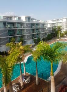 a hotel with palm trees in front of a swimming pool at Apartment Tenerife Sur in Palm-Mar