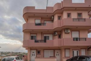 a pink building with cars parked in front of it at Faidra 03 at TEI in Heraklio