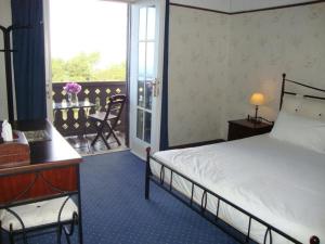 a bedroom with a bed and a desk and a balcony at Elafos Hotel in Sálakos