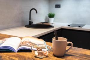 an open book on a table with a cup and a mug at Modern and Design Apartment near the Main Square in Zagreb
