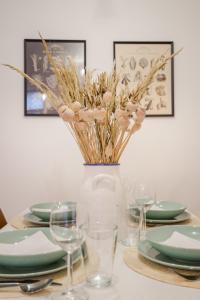 une table avec des assiettes et des verres et un vase avec des fleurs dans l'établissement ROOMLI Boho Chic Apartments, à Budapest