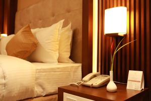 a hotel room with a bed and a phone on a table at Magnet Hotel in Kannur