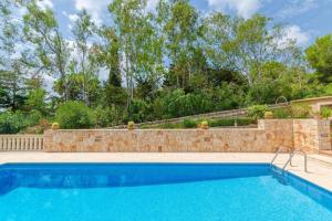a swimming pool with a stone retaining wall and a stone fence at Es Turó de França in Calonge