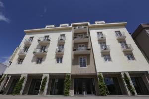 een hoog wit gebouw met ramen en balkons bij Hotel Villa Grace in Međugorje