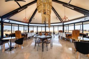 uma sala de jantar com mesas, cadeiras e lustres em Etosha King Nehale em Omuthiya