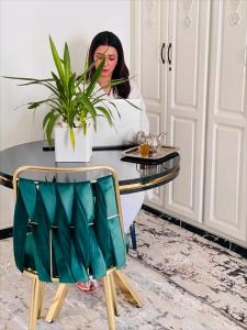 a woman sitting at a table with a plant at Aparthotel & Hotel Doha in Nador