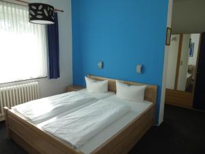 a bedroom with a large bed with a blue wall at Hotel Süden in Berlin