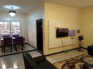 a living room with a table and a tv on a wall at Kër Adja in Ziguinchor