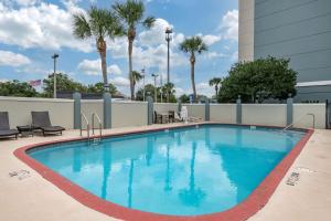 a large swimming pool with chairs and palm trees at Comfort Suites Baymeadows Near Butler Blvd in Jacksonville