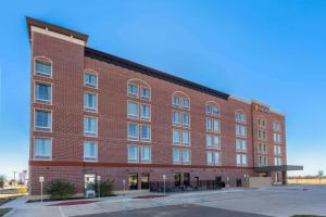 um grande edifício de tijolos vermelhos com muitas janelas em La Quinta Inn & Suites by Wyndham Dallas - Frisco Stadium em Frisco