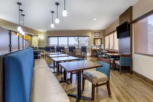 a dining room with tables and chairs and a tv at Comfort Suites in Hobbs