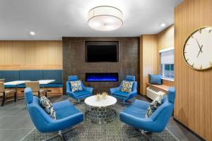 a waiting room with blue chairs and a clock at Microtel Inn & Suites by Wyndham Farmington in Canandaigua