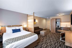 um quarto de hotel com uma cama grande e uma cozinha em Microtel Inn & Suites by Wyndham Farmington em Canandaigua