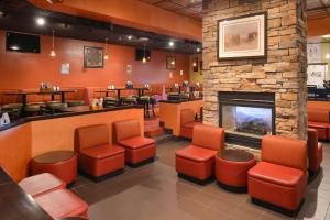 a restaurant with a fireplace and chairs and a bar at Ramada Plaza by Wyndham Sheridan Hotel & Convention Center in Sheridan