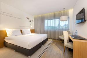 una camera d'albergo con letto, scrivania e TV di TRYP by Wyndham Leiria a Leiria