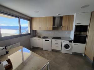 a kitchen with white appliances and a large window at MONTE AZUL Faro de Cullera in Faro de Cullera