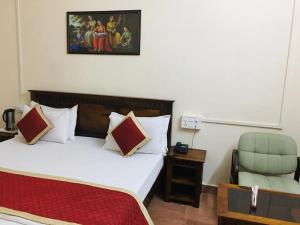 um quarto de hotel com uma cama e uma cadeira em Rose Cottage - A Heritage Retreat em Monte Abu