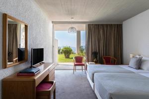 a hotel room with two beds and a television at Amalia Hotel Delphi in Delphi