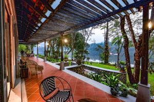 a patio with chairs and a view of the mountains at Periyar River Lodge in Thattakād