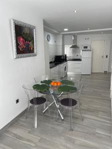 cocina con mesa de cristal y sillas en una habitación en Apartamento 2 Gran8Nerja, en Nerja