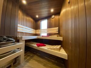 a small room with wooden walls and bunk beds at Ferienhaus am Meer mit Kamin & Sauna - Seestern 251 in Julianadorp