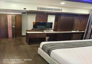 a hotel room with a bed and a flat screen tv at Hotel M Grand in Chennai