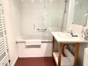 a white bathroom with a sink and a tub at Hôtel - Restaurant "Histoire de Bistrot" in Isbergues