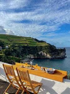 einen Tisch mit 2 Stühlen und Meerblick in der Unterkunft Baía dos Moinhos in Ribeira Grande