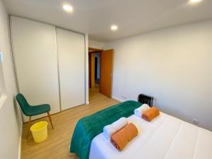 a bedroom with a bed and a green chair at Baía dos Moinhos in Ribeira Grande