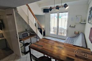 a small room with a wooden table and a microwave at Joli T2 avec clim, 4/6 personnes,500m de la plage. in Saint-Cyprien