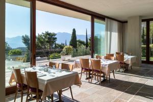 un restaurante con mesas, sillas y ventanas grandes en Amalia Hotel Delphi, en Delfos