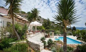 a house with a swimming pool and palm trees at Studio apartment in Orebic with sea view, terrace, air conditioning, WiFi 114-3 in Orebić