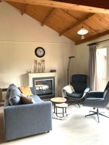 sala de estar con sofá, sillas y reloj en Familie Meys Chalets - Chalet 236 - La Boverie, en Rendeux