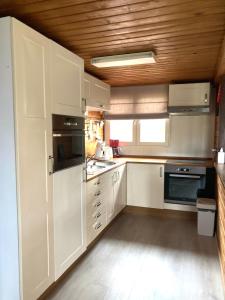 cocina con armarios blancos y techo de madera en Familie Meys Chalets - Chalet 236 - La Boverie, en Rendeux