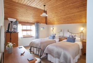 a bedroom with two beds and a wooden ceiling at Dairy Barns in Hickling