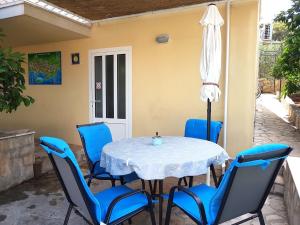 a table with chairs and a umbrella on a patio at Villa Radoš - 4 Sterne, 3 Apartments für maximal 18 Gäste in Supetar