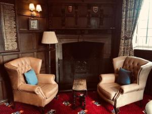 salon z 2 krzesłami i kominkiem w obiekcie Woodsome Hall Golf Club Dormy House w mieście Fenay Bridge