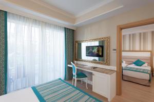 a bedroom with a bed and a desk with a television at Karmir Resort & Spa - Ultra All Inclusive in Kemer