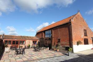 a brick building with tables and chairs on a patio at Dairy Barns in Hickling