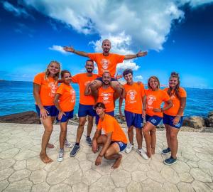 a group of people wearing orange shirts on the beach at Cala Rosa Club Hotel in Stintino