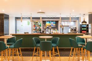 un bar en un restaurante con mesas y sillas verdes en Holiday Inn Southampton Eastleigh, an IHG Hotel, en Eastleigh