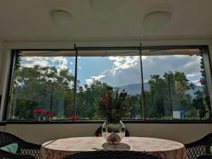 a table with a vase with flowers on it in front of a window at Sandy's Superior Suite in Ancient Epidauros