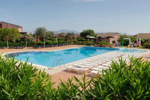 a large swimming pool with lounge chairs in a resort at Cala Rosa Club Hotel in Stintino