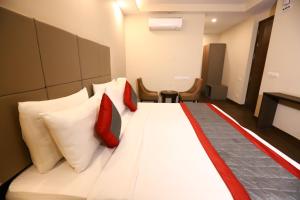 a hotel room with a bed with red and white pillows at Hotel Azulo Inn Bhikaji Cama Place Delhi in New Delhi