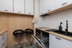 a kitchen with two stools next to a dishwasher at City Center Apartment Gdynia by Renters in Gdynia