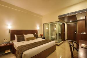 a bedroom with a large bed and a glass shower at Hotel Express Residency Vadodara in Vadodara