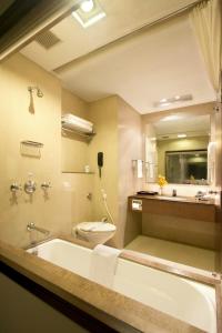 a bathroom with a tub and a toilet and a sink at Hotel Express Residency Vadodara in Vadodara