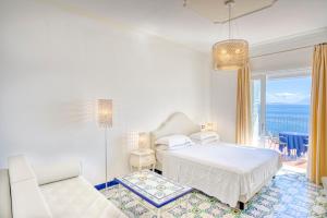 a white bedroom with a bed and a balcony at Hotel Cetus in Cetara +37 photos